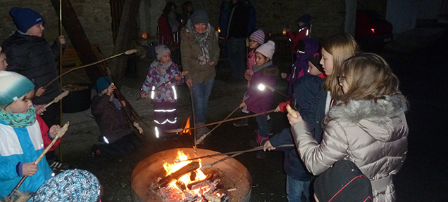 Kinder mit Stockbrot um eine Feuerschale